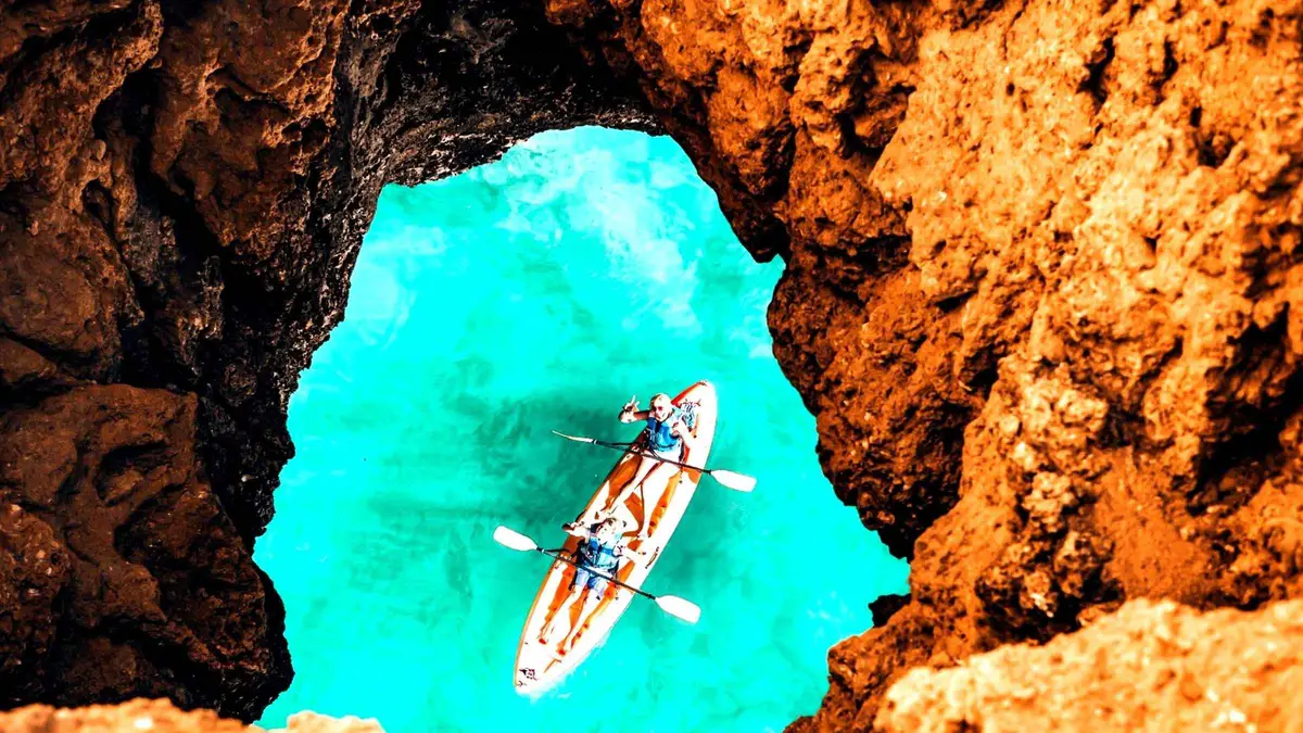 Kayakers paddling into a sea cave beneath the cliffs at Praia do Castelo on a guided kayak trip, one of the best-rated things to do in Albufeira, Algarve