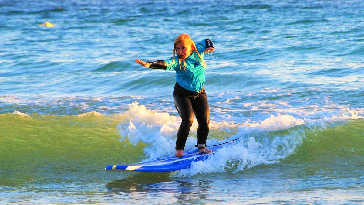 Surf instructor guiding a beginner onto a wave at Galé Beach near Albufeira during a surf lesson, one of the family-friendly things to do in Albufeira, Algarve